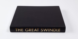 This is the book cover from ''The Great Swindle'''s book which compiles all of the artworks by artist Santiago Montoya part of that series.