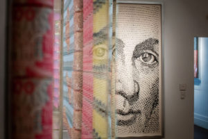 View of work of art ''The General and his labyrinth'' via the side of work of art 'Let´s Do the Numbers' by artist Santiago Montoya. He is making us look at the aesthetic and the material aspects of money.